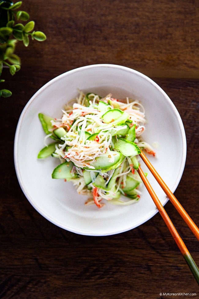 Korean cucumber crab salad served on a white plate with chopsticks