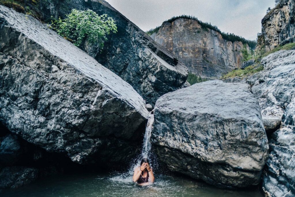 a person in a body of water under a rock