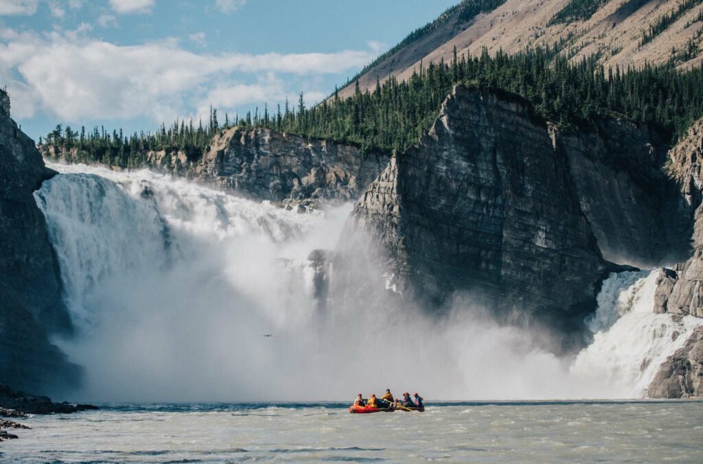 a group of people in a boat on a river with a waterfall