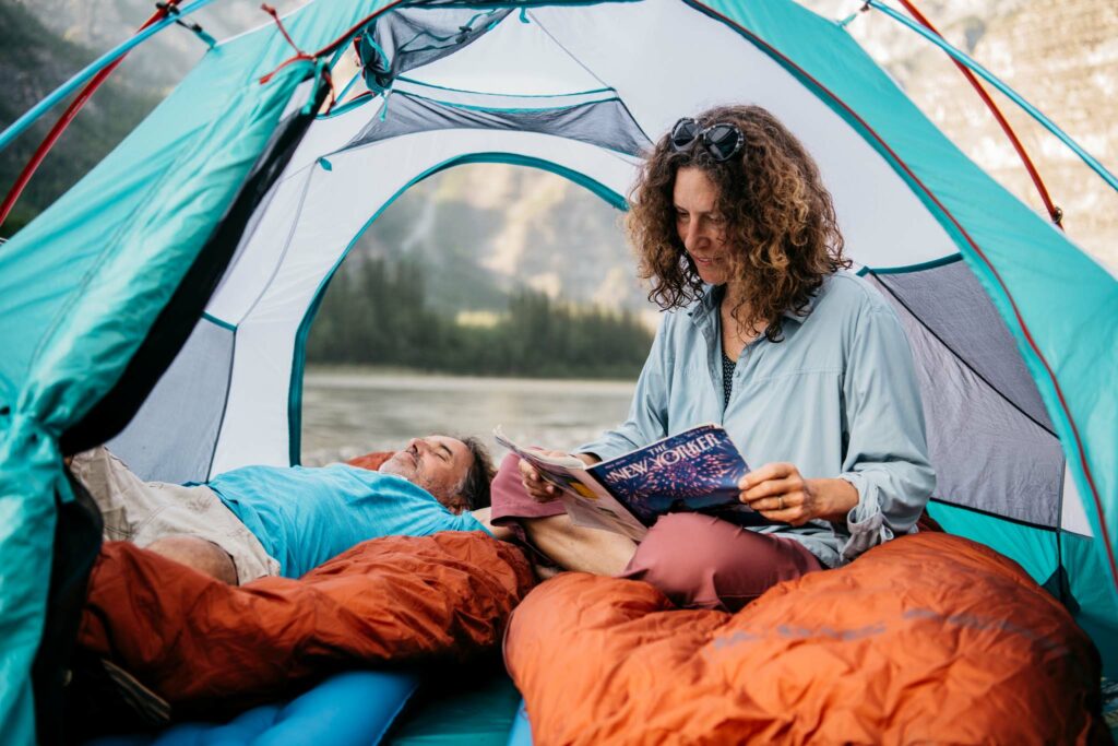 a woman and a man lying in a tent