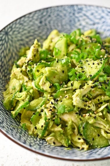 A side view of a blue serving bowl filled with Avocado and Chicken Salad.