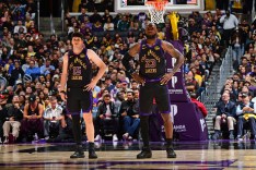 LeBron James and Austin Reaves on the court in their black and yellow Lakers uniforms.