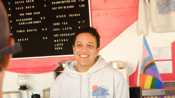Staff member Allissia at the counter in front of the cafe menu