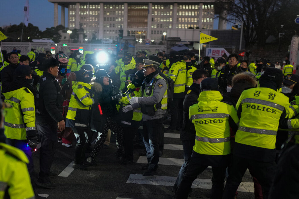 上个月,尹锡悦总统宣布实施戒严后几个小时后,警察和抗议者聚集在首尔国会大厦外。