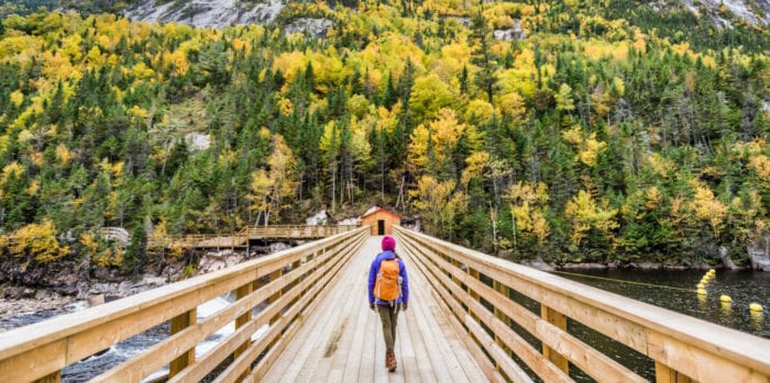 activities-hike-image@2x | Trans Canada Trail Woman walking down wooden bridge towards forest