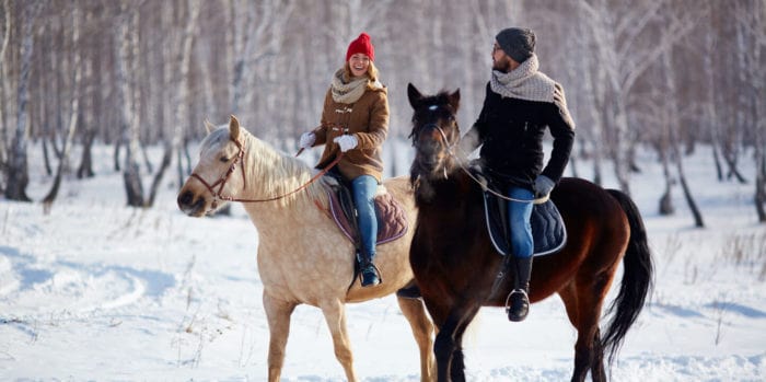 activities-ride-image@2x | Trans Canada Trail A couple horseback riding in a snowy forest