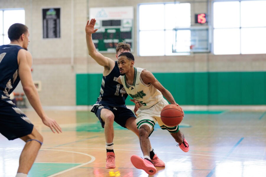 A basketball player dribbling the ball past an opponent