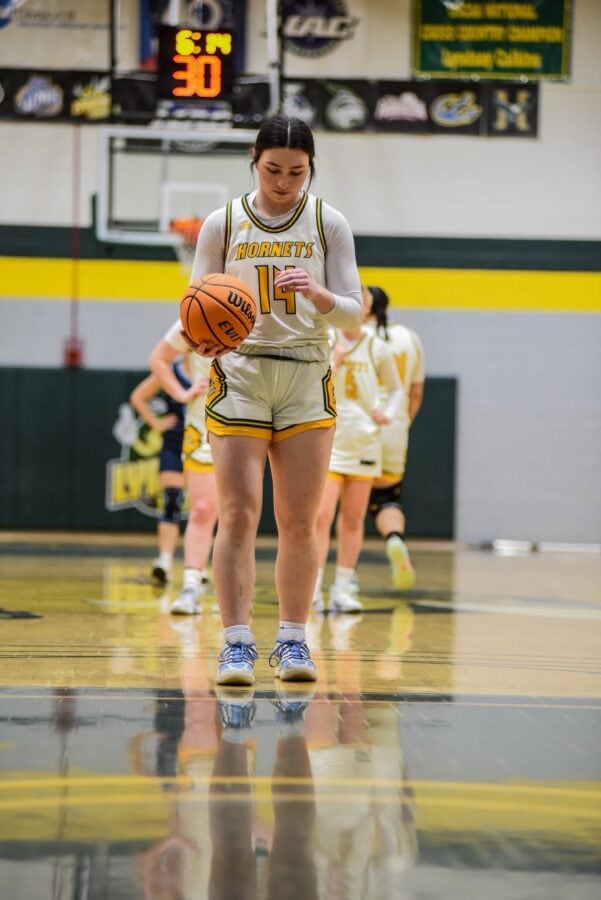A women's basketball player mid dribble looking down at the court
