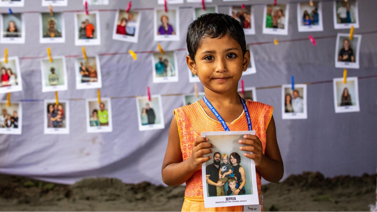 A child holds a photo of their sponsor