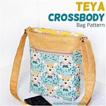 a finished handmade crossbody tote in camel yellow suede and a beautiful, deer-printed quilting cotton with an edge of a samsung phone visible on the table