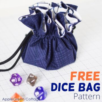 a finished sewn dice pouch in a dark denim print next to several colorful dices