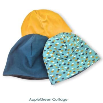 Three handmade reversible knit beanie hats in solid and print fabrics, finished sewing project.