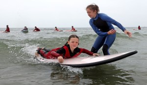 Surf Camp Camp councilor, Hannah Duran works with a camper at Northeast Surfing Academy on Nantasket Beach. (Matt Stone/Boston Herald).