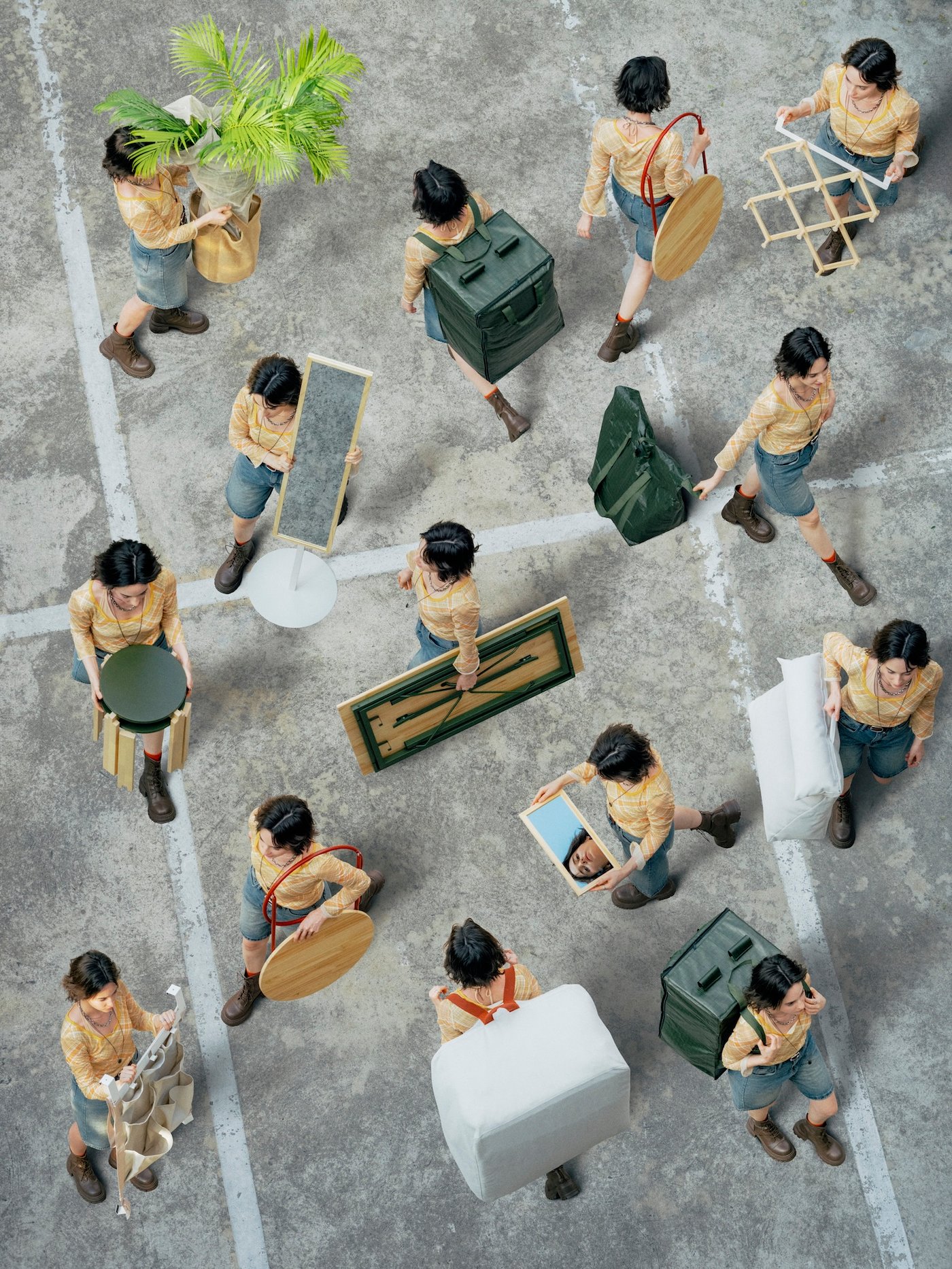 Overhead view of a multiple versions of a person walking in a car park, each carrying a different product from the KOMPISHÄNG collection.