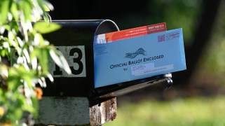 A mail-in ballot sticking out of a mail box.