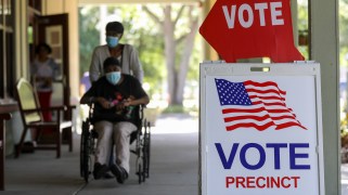 a woman pushes another woman in a wheelchair toward a polling place.