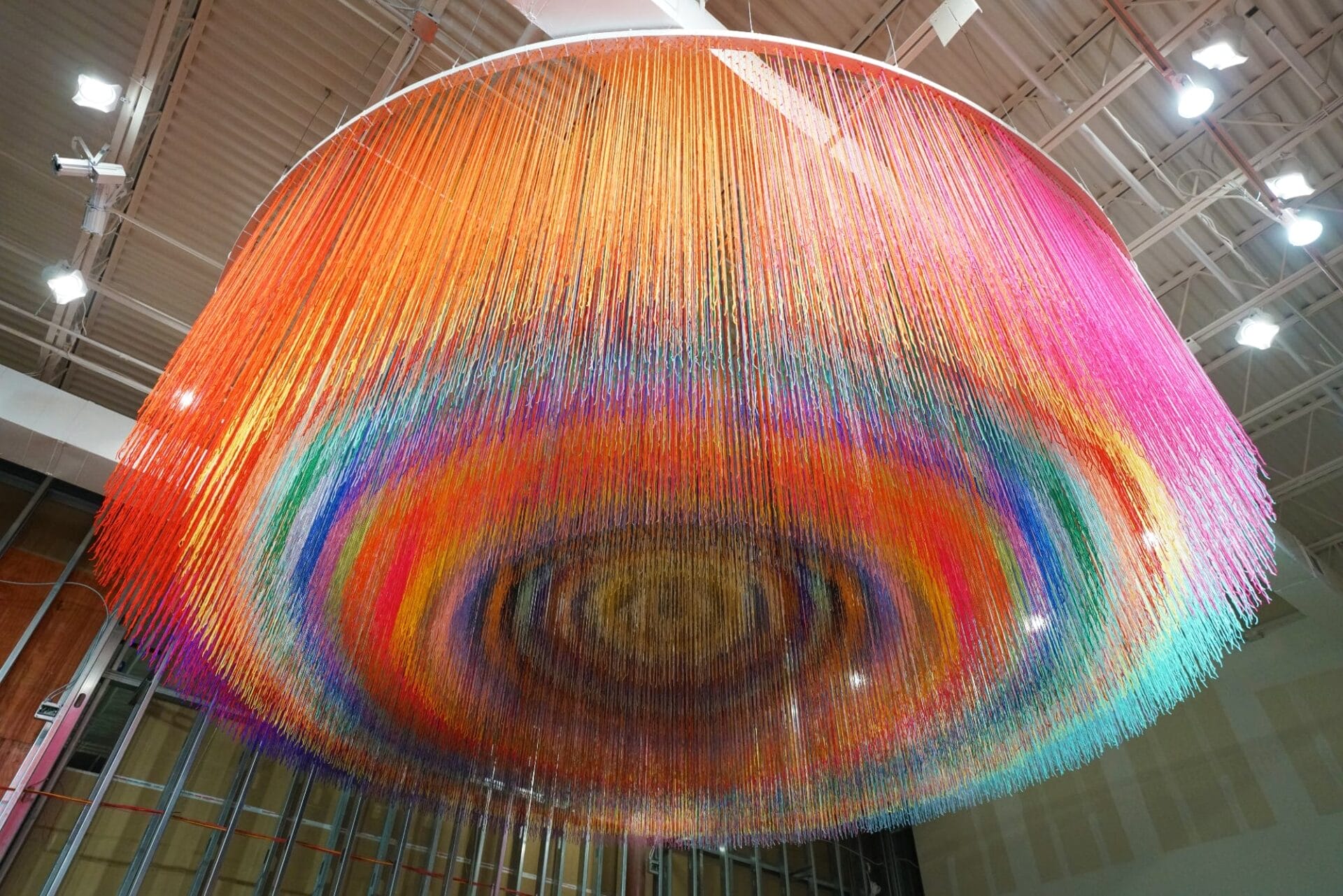 a suspended sculpture with colorful fibers in concentric circles