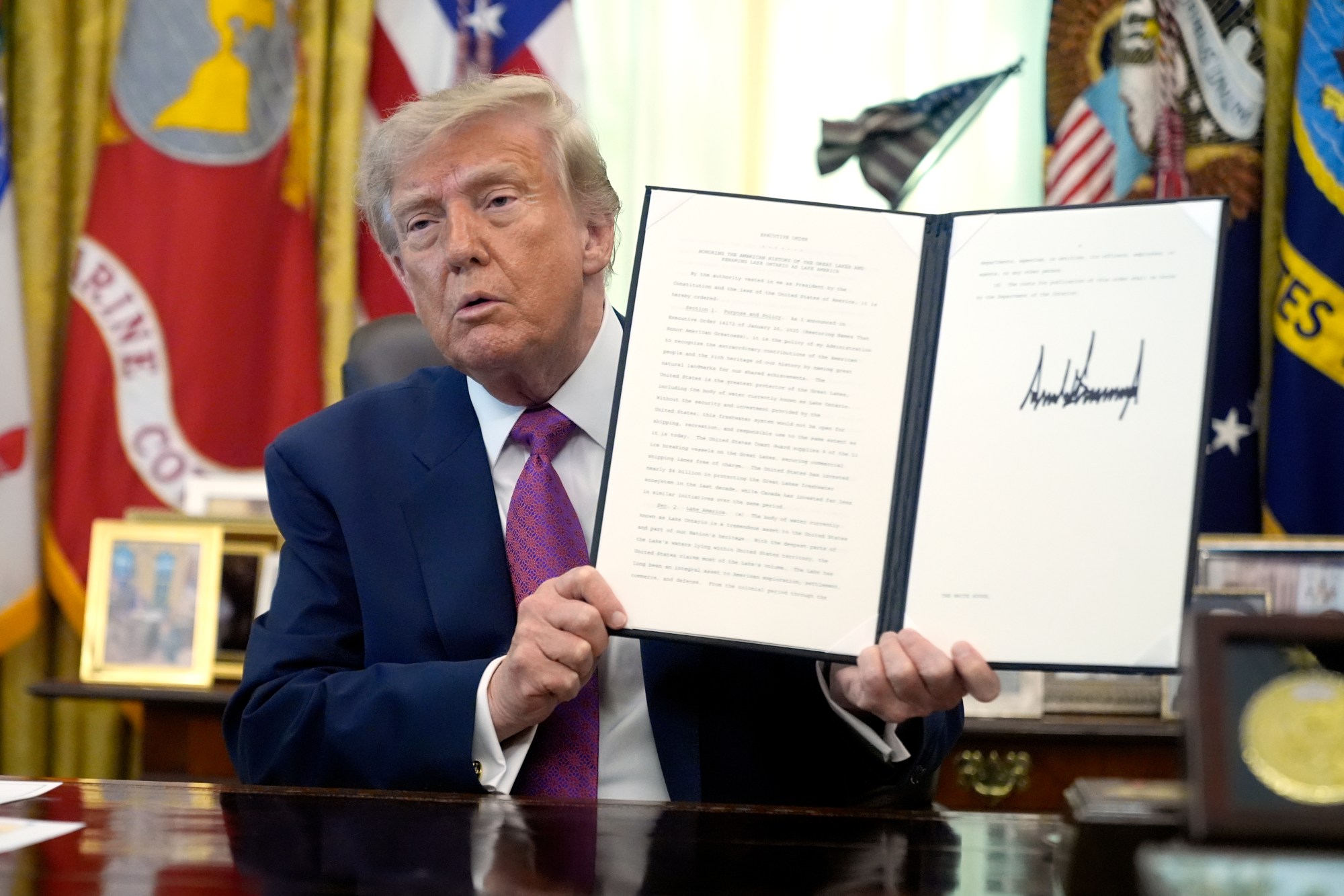 AP26239645255623 President Donald Trump holds up a signed executive order in the Oval Office of the White House, Thursday, Aug. 27, 2026, in Washington. (AP Photo/Manuel Balce Ceneta)