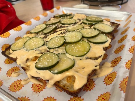 STP-L-BRICKSWORTH-02 A pizza with burger sauce, pickles and sesame seeds on it