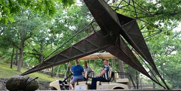 STP-L-CAPONI-0817 People view a sculpture from a golf cart tour.