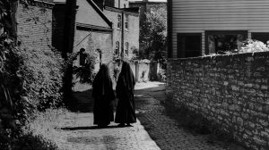 STP-L-THROWBACK-0813 cropped Two nuns walk away from the camera down a cobblestone alley with buildings on either side.