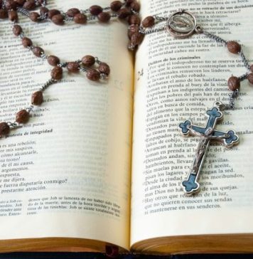 Catholic Books That Bring Reflection Into Everyday Life silver cross pendant necklace on book page